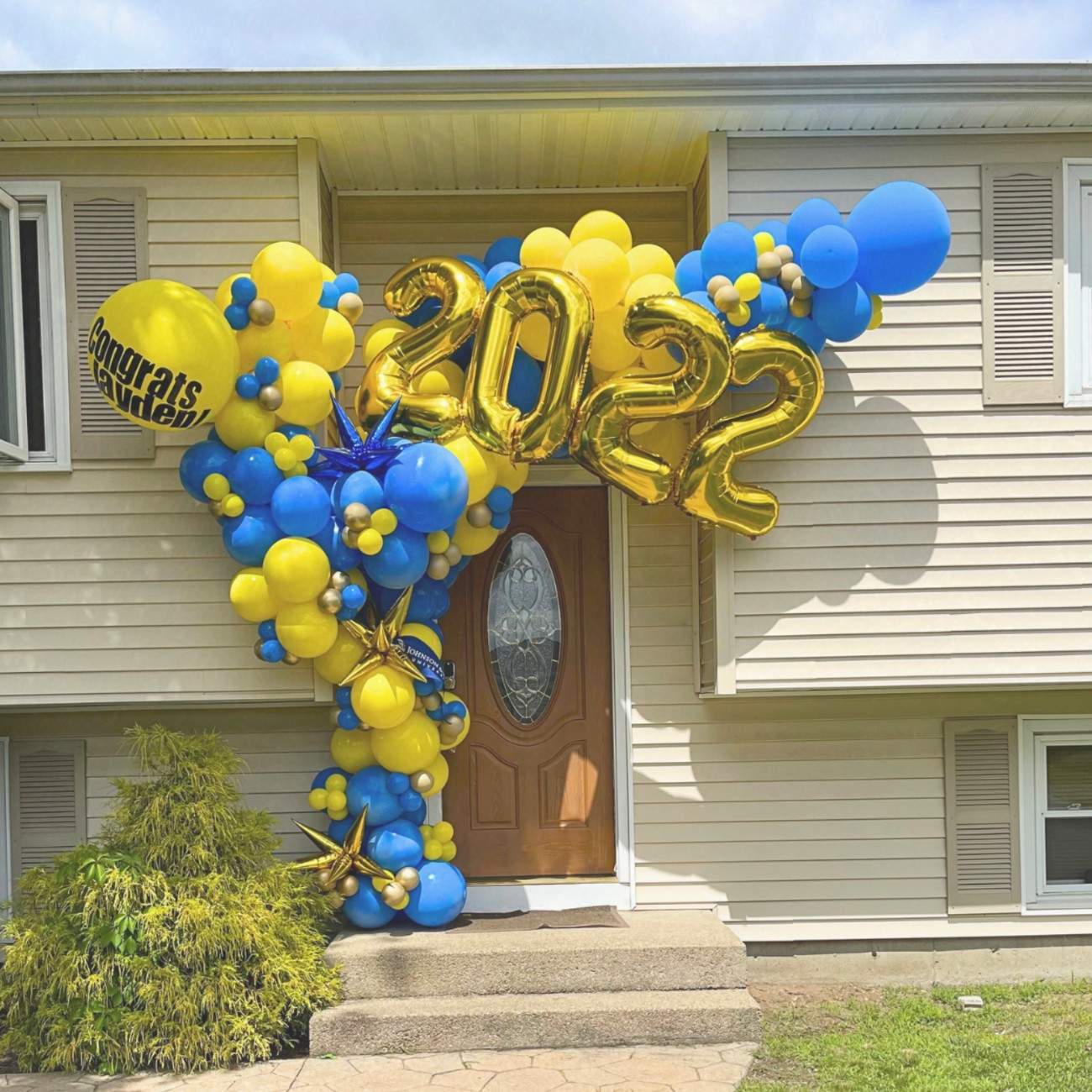 Decorative balloon arch with 'Congrats 2022' on a house front door.