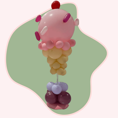 Balloon sculpture of a character with pink, yellow, and purple colors on a green background