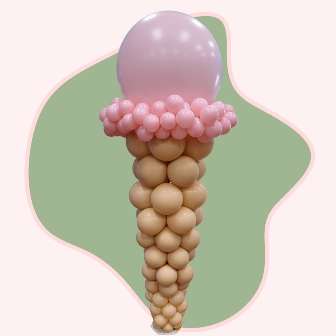 Balloon sculpture of an ice cream cone with pink top on a green and white background