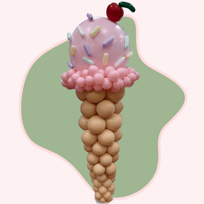 Balloon sculpture of an ice cream cone with pink top and cherry on a green and white background