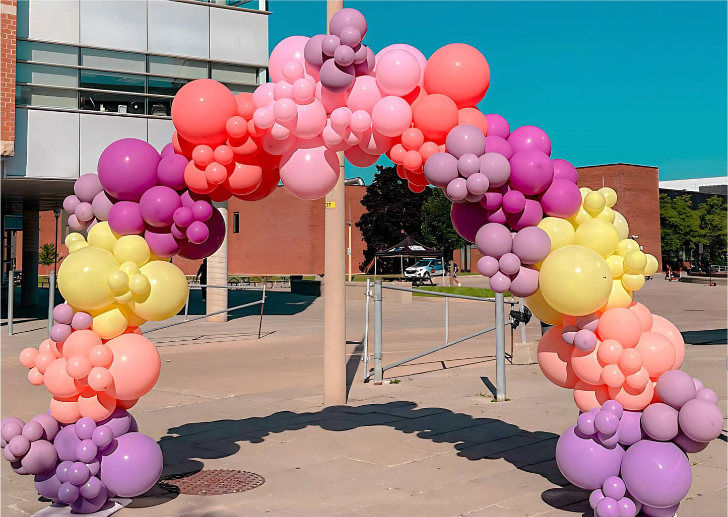 Colorful balloon arch in front of a building with a clear blue sky.